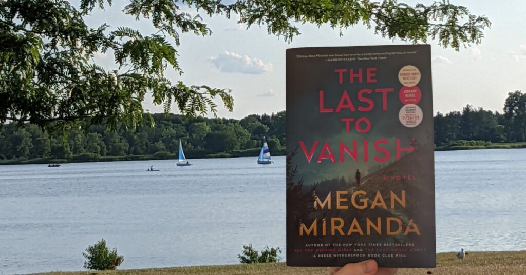 A copy of The Last to Vanish held up against a background of a lake with sailboats