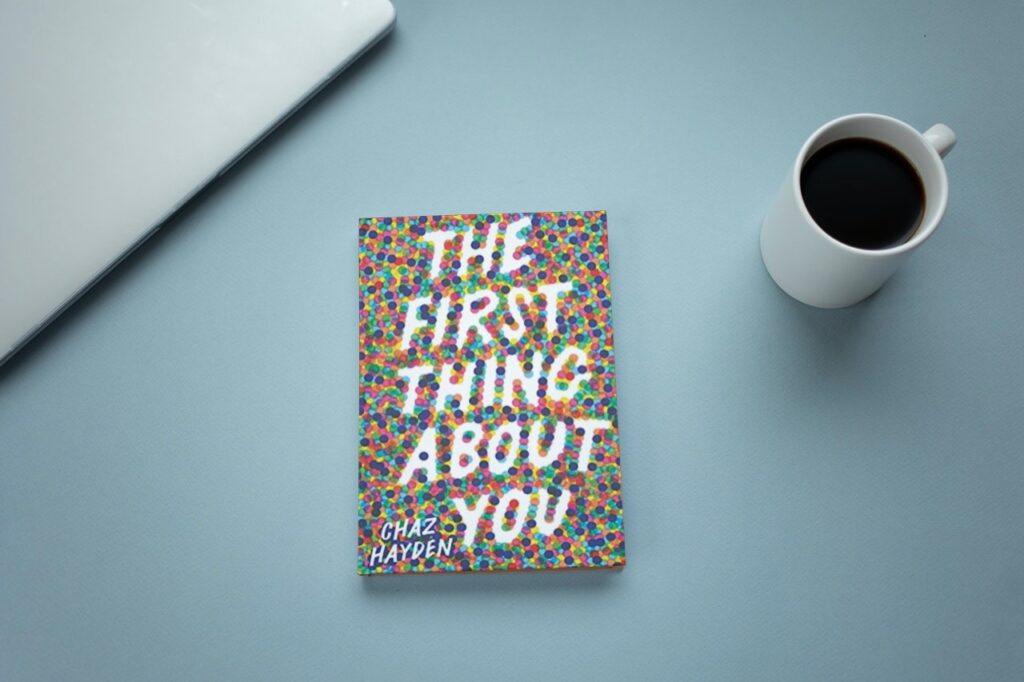 A desk and cup of coffee with a copy of The First Thing About You