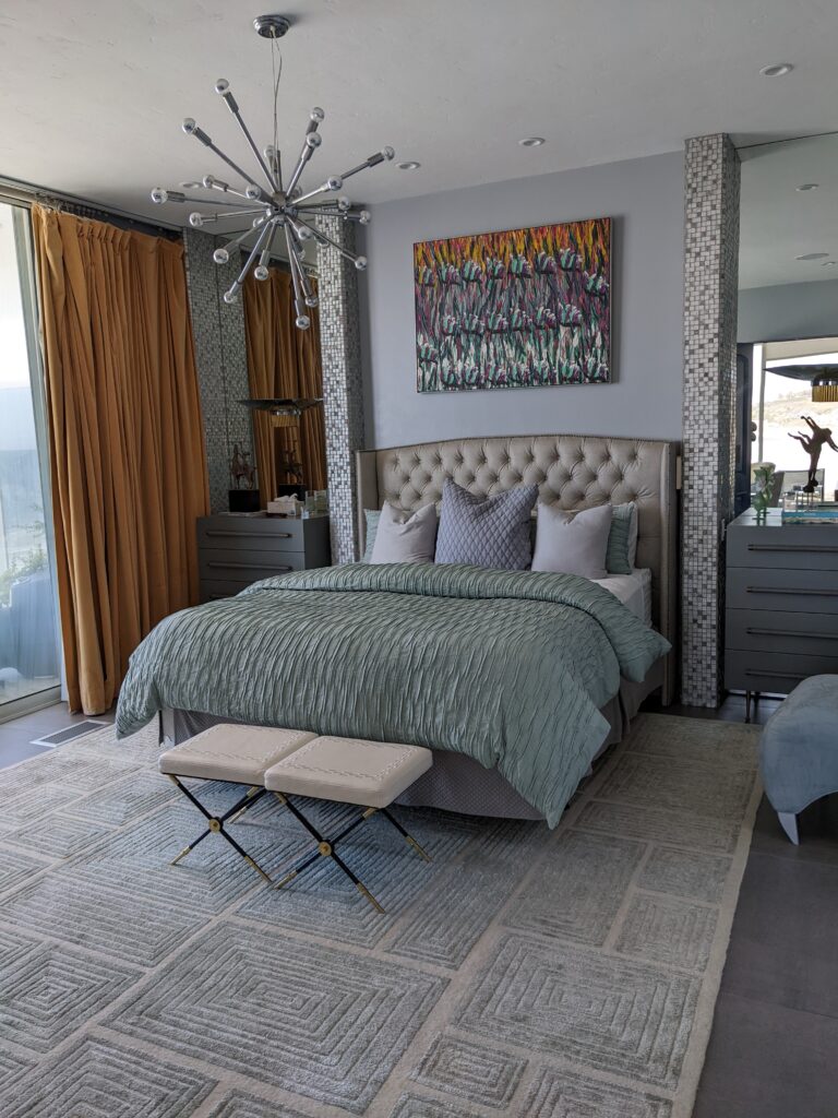 The master bedroom in Malibu showing a large bed with fluffy pillows, yellow curtains, a light fixture, and a painting on the wall