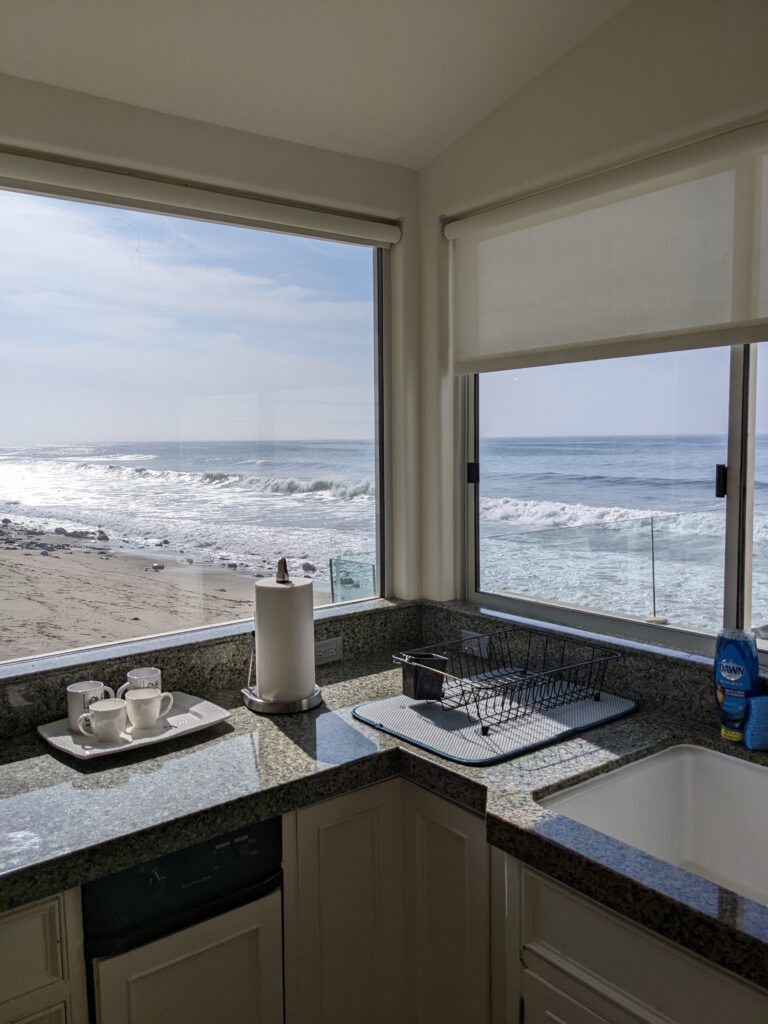 The kitchen in Malibu showing 4 white mugs on the counter with the waves of Malibu in the background